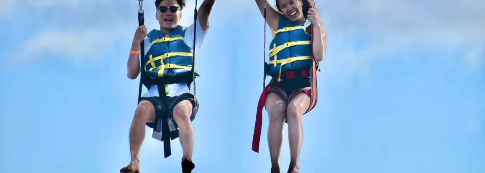 Couple hold hands while parasailing