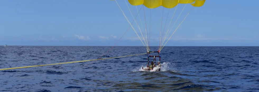 Friends dunk in waikiki ocean while parasailing