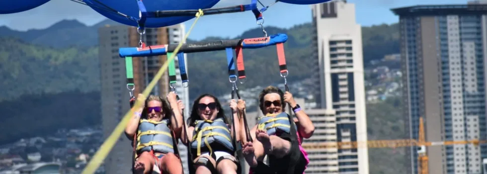 Friends parasail with honolulu city background
