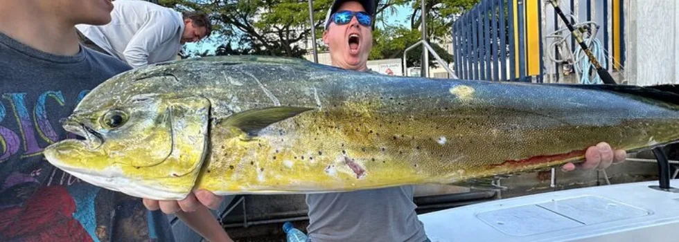 Man poses with mahi mahi after waikiki fishing charter
