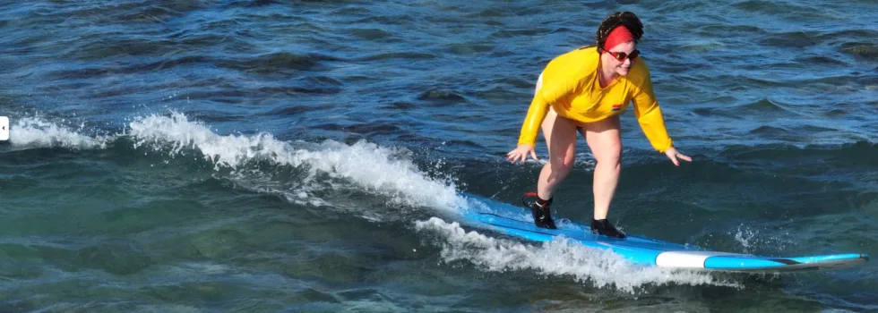 Woman catches wave during waikiki surf lesson