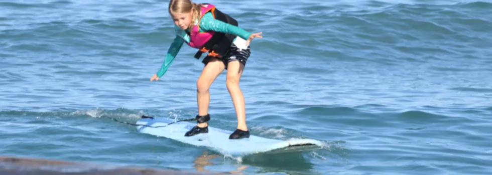 Child surfer in life jacket riding waikiki wave