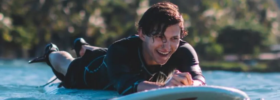 Man smiling while laying on surfboard
