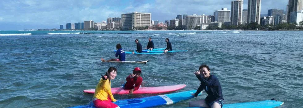 Surf teacher waves with students in waikiki