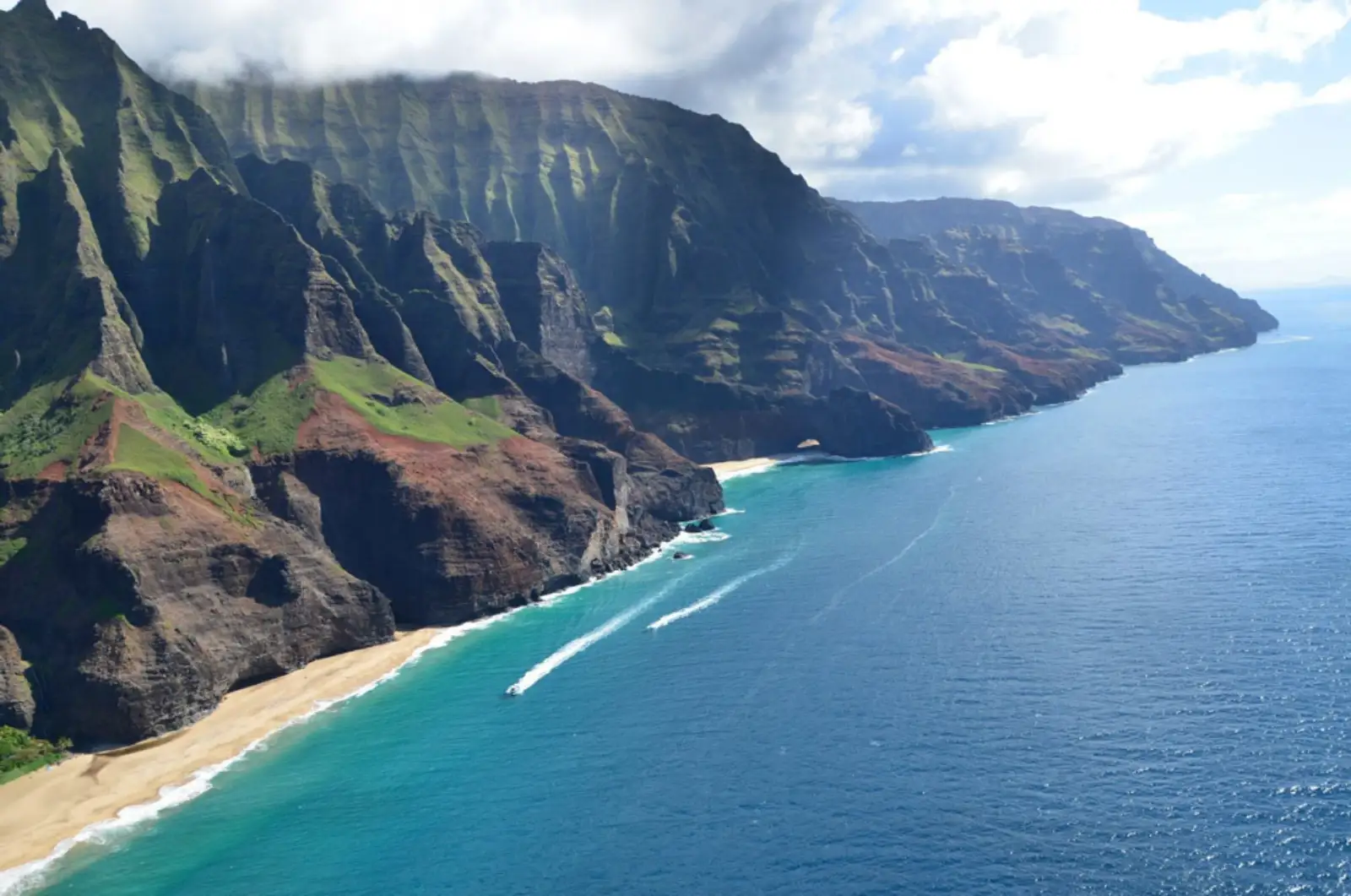 The Na Pali Coast's green sea cliffs, with tour boats below