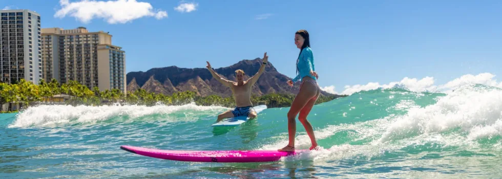 Girl learns to surf while instructor cheers