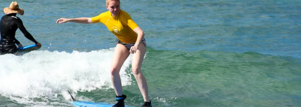 Woman catching wave during kauai surf lesson