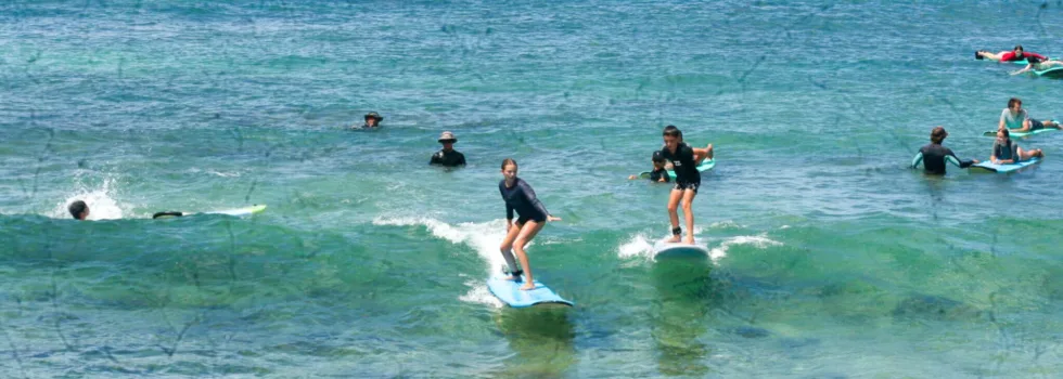 Girl rides waves in clear water poipu