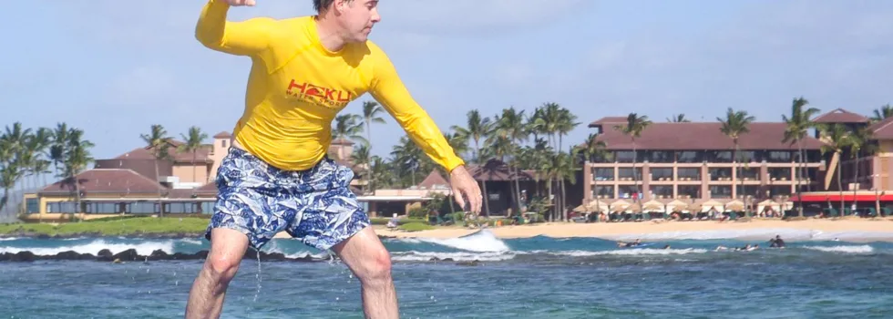 Man riding wave during poipu surf lesson