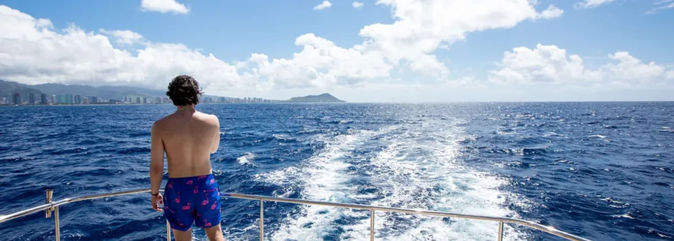 Guy watches diamond head from back of boat