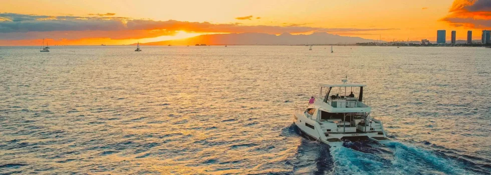 Luxury power catamaran drives toward waikiki sunset