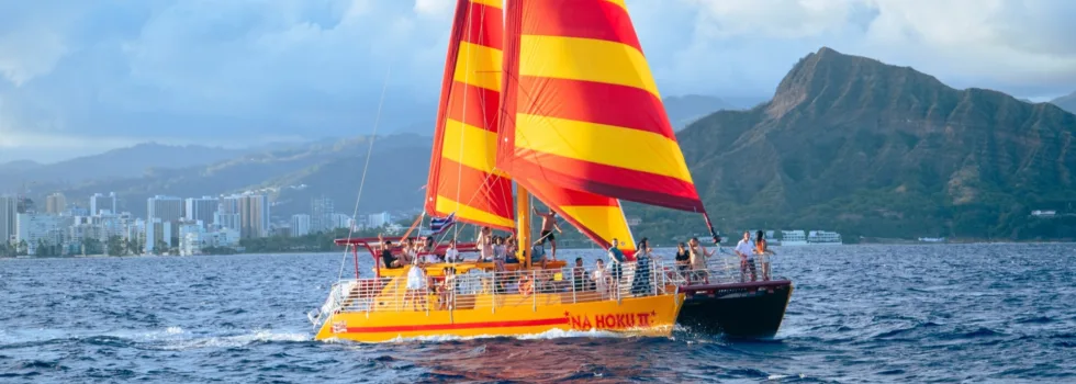 Yellow and red catamaran sailing past diamond head waikiki