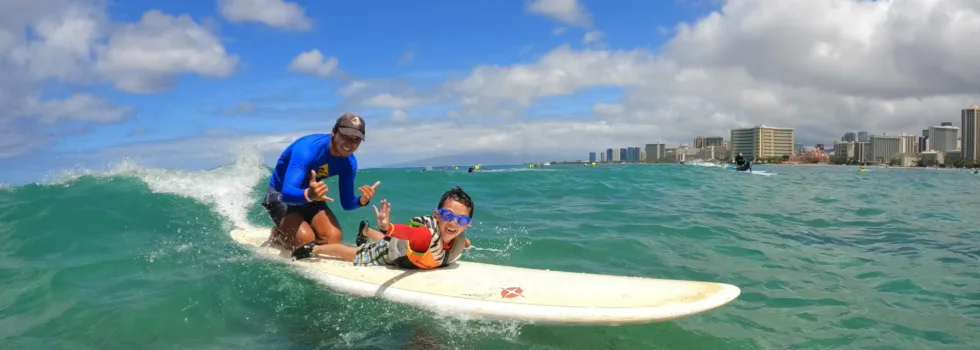 Instructor and child tandem surfing waikiki