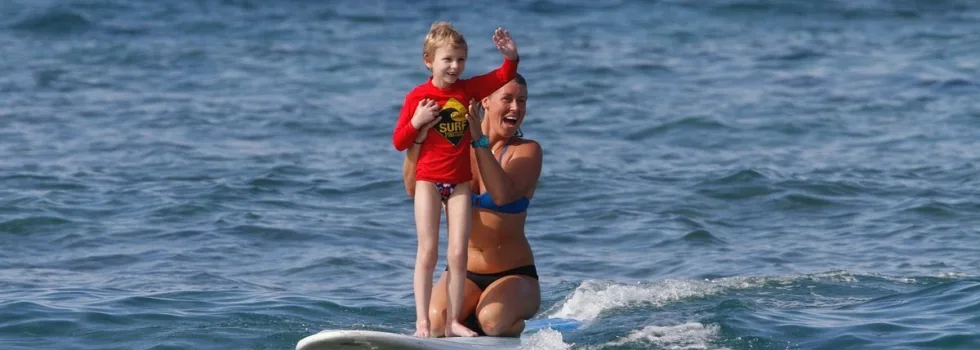 Little girl waving while surfing