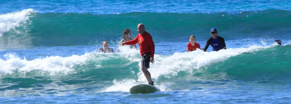Older gentleman riding wave during waikiki surf lesson