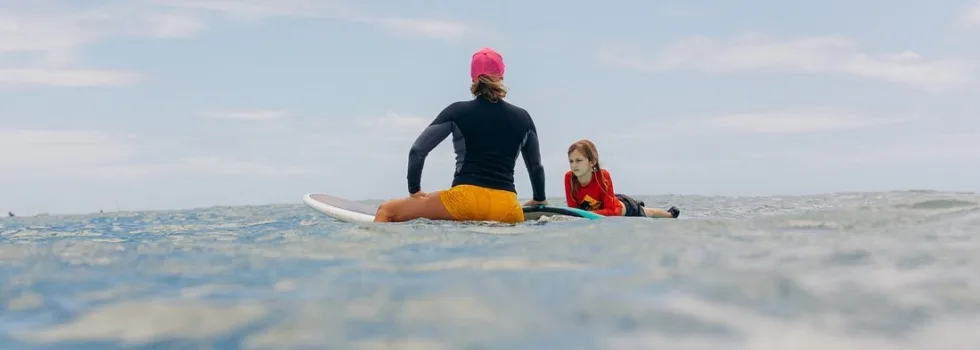 Surf teacher waiting for waves with student