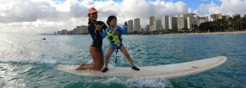 Young girl surfs with teacher