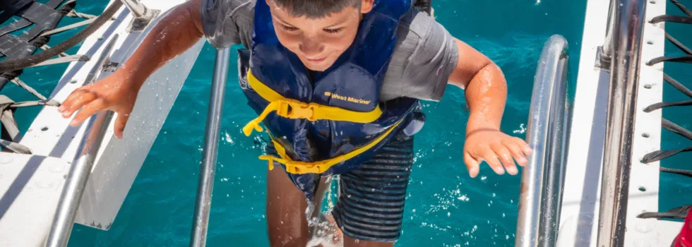 Kid climbing up waikiki catamaran ladder
