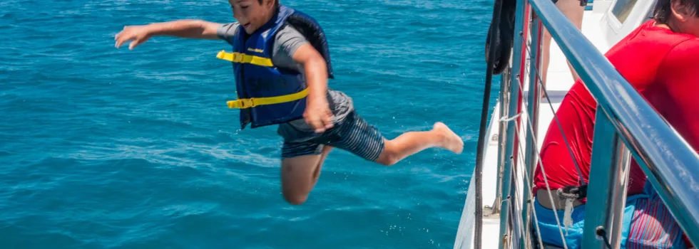 Kid jumping from catamaran