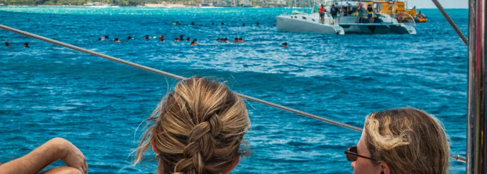 Girls viewing waikiki snorkel spot from catamaran net