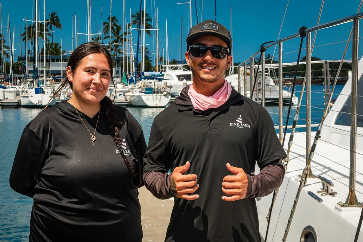 Tour guide assisting guests board catamaran in Ala Wai Harbor