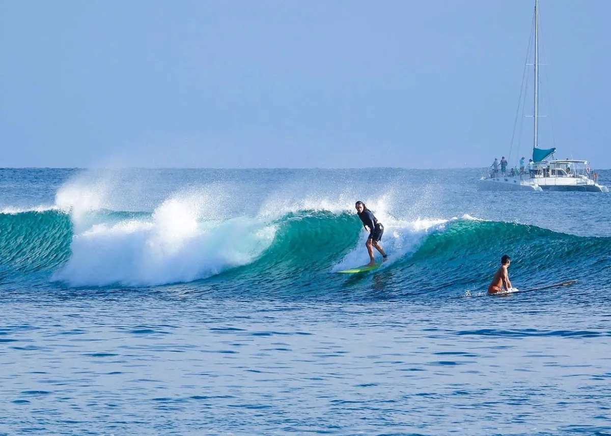 Surfer at Ala Moana bowls catching a wave outside of Ala Wai harbor