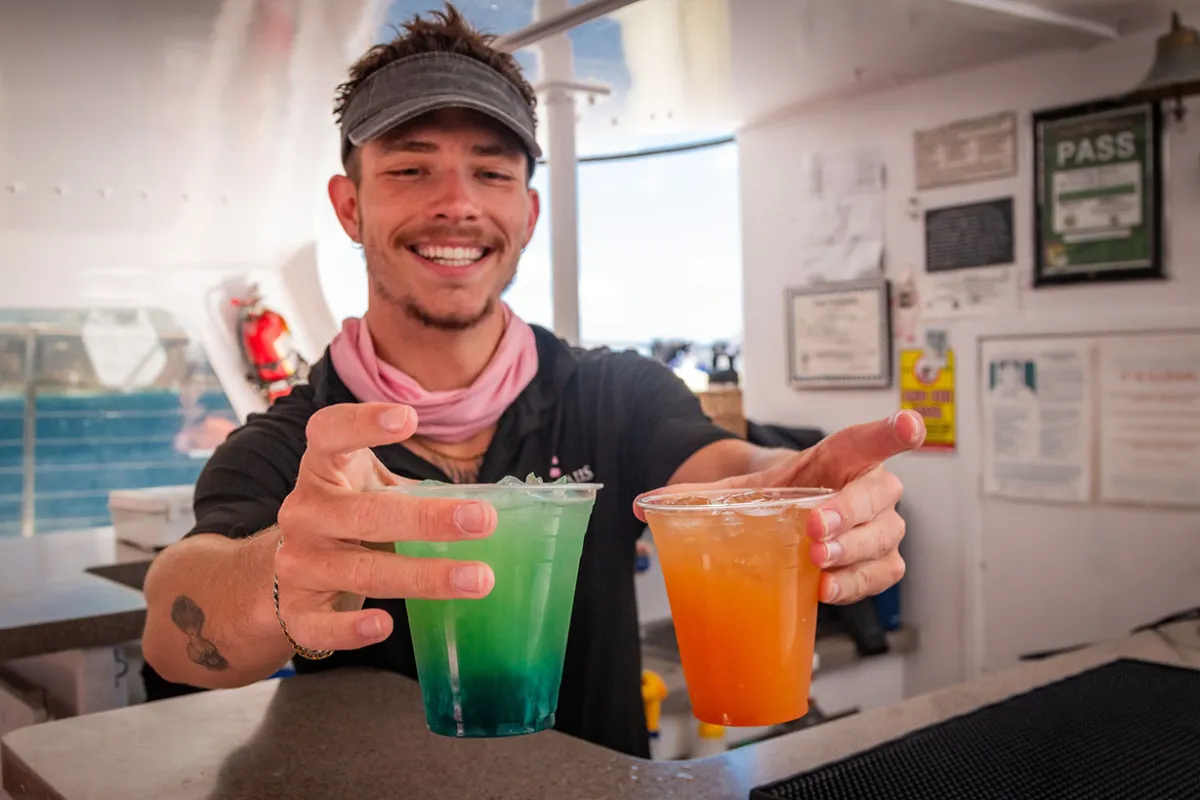 Crew member serving cocktails below deck on turtle canyon snorkeling tour